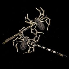 three silver spider brooches on a black background, with one attached to the other