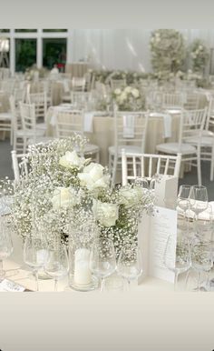 the tables are set up with white flowers and wine glasses for an elegant wedding reception