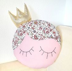 a pillow with a crown on top of it and eyes painted on the back of it