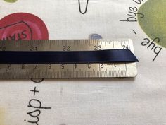 a measuring tape is on top of a piece of fabric with an apple design and blue ribbon