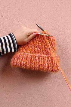 a person holding a pair of scissors next to an orange knitted heart