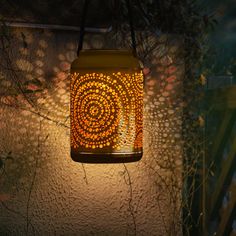 a lantern hanging from the side of a building with an artistic design on it's front