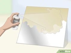 a hand holding a spray paint can next to a piece of paper with the shape of a map on it