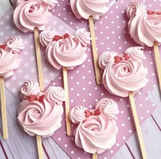 some pink cupcakes sitting on top of wooden sticks