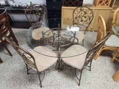 a glass table with four chairs around it in a room filled with furniture and other items