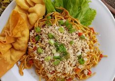 a white plate topped with pasta and veggies next to tortilla chips