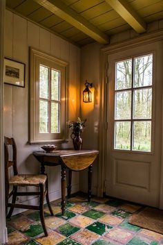 a room with a table and two chairs in front of a door that leads to another room