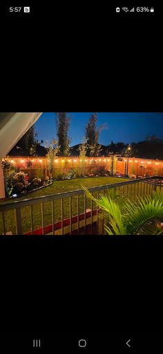 an image of a backyard at night with lights on the fence and plants in the yard