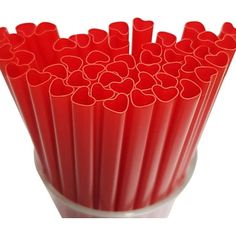 red plastic straws with hearts on them in a white cup, isolated against a white background