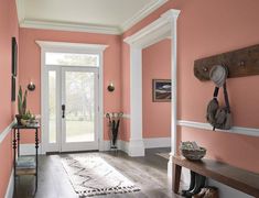 an entry way with pink walls and wooden flooring in the hallway, along with a bench