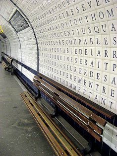 several benches are lined up in front of a wall with words written on the walls