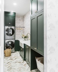 a washer and dryer in a small room with green cabinets, marble flooring