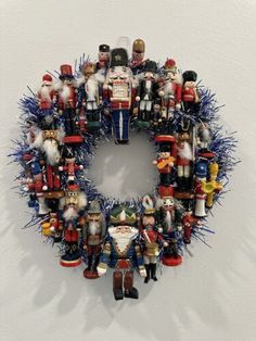 a christmas wreath made out of nutcrackers and other holiday decorations on a white wall