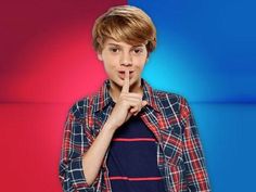 a young man making a hush with his finger on his lips while standing in front of a red and blue background