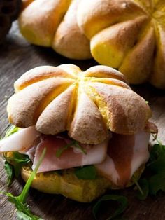 a sandwich with ham, cheese and lettuce sitting on top of a wooden table