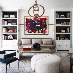 a living room filled with furniture and bookshelves next to a painting on the wall