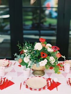 an arrangement of flowers in a vase on a table with red and white napkins