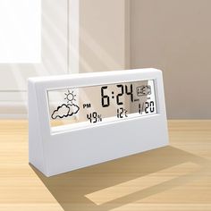 an alarm clock sitting on top of a wooden table in front of a window with the sun behind it