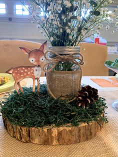 a mason jar filled with fake flowers and deer figurines on top of a table