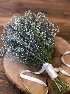 a bunch of flowers sitting on top of a wooden table next to a white ribbon