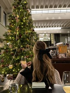 a woman sitting in front of a christmas tree