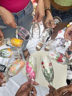 several people are holding wine glasses in the middle of a circle on a white table cloth