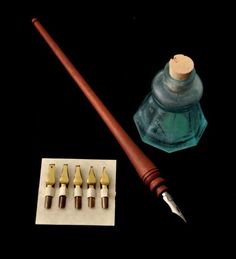 a pen, ink bottle and other items on a black background