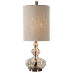 a glass table lamp with a beige shade