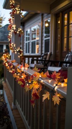 the fall leaves are hanging from the railing on the house's front porch at night