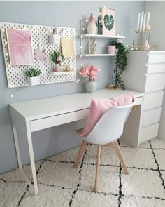 a white desk topped with a pink pillow next to a shelf filled with plants and flowers