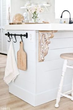 a white kitchen with an island and wooden stools