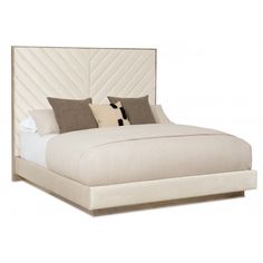 a white bed with two pillows on it and a headboard made out of fabric