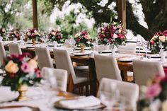 a long table set up for a wedding reception with flowers and place settings on it