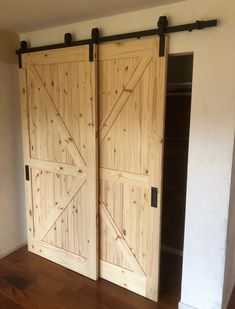 two wooden doors are open in a room with hardwood floors and white walls, along with a hard wood floor