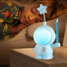 a little boy laying in bed next to a night light