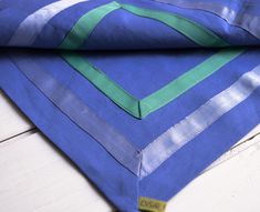 a blue and green striped cloth on top of a white wooden table with a yellow tag