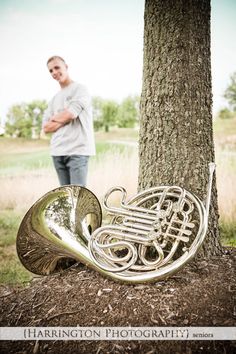 a man standing next to a tree with a trumpet in front of him on the ground