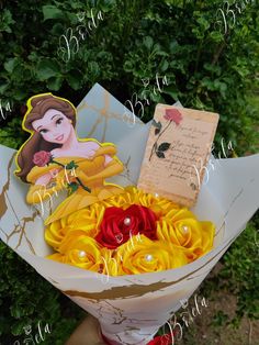 a bouquet of yellow and red flowers with a note on it in front of some bushes