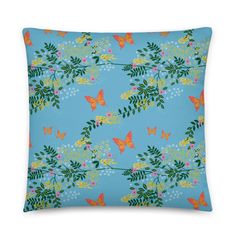 a blue pillow with orange butterflies and flowers on the front, against a white background