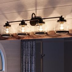 a bathroom vanity light with mason jars on the top and lights above it in front of a window