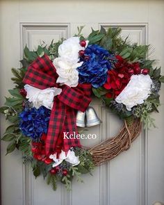 a wreath with red, white and blue flowers is hanging on the front door to welcome guests