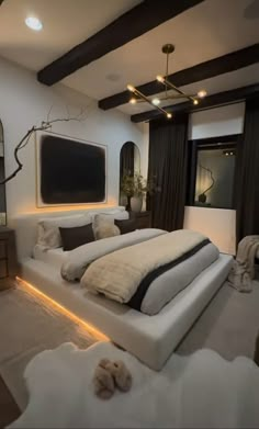 a large white bed sitting in a bedroom next to a tv mounted on the wall