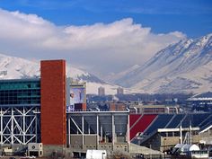 a large building with mountains in the back ground and snow on the top of it