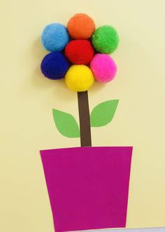 a paper flower with pom - poms in it on a yellow wall background