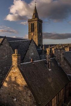 an old building with a clock tower in the middle of it's roof tops