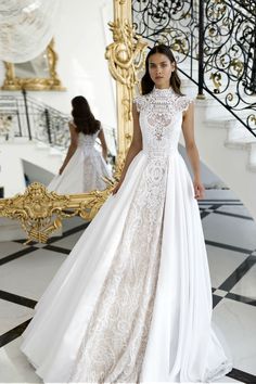 a woman standing in front of a mirror wearing a wedding dress