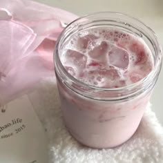 a pink drink in a glass with ice cubes on it next to an envelope