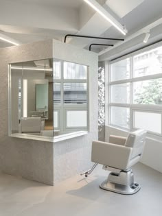 a white chair sitting in front of a window next to a bathtub and sink