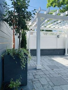 a white pergolan sitting next to a tall planter