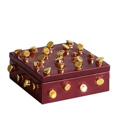 a red and gold chess board with golden pieces on the top, sitting in front of a white background